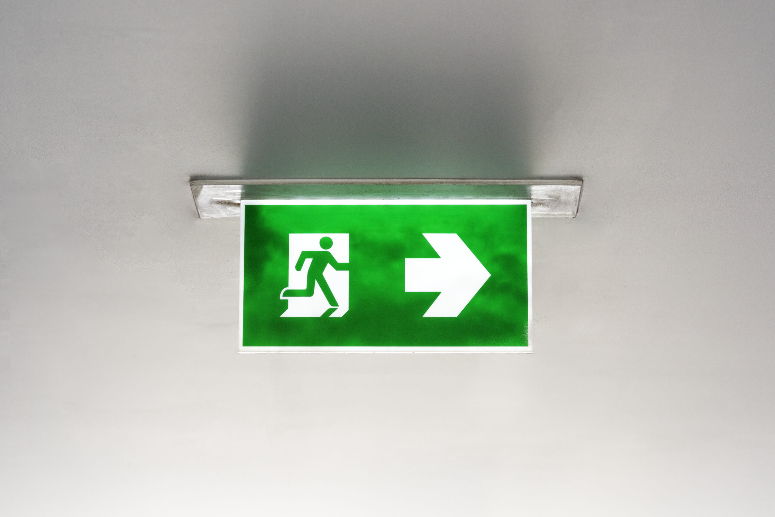 Green emergency exit sign on the ceiling who we are - 2